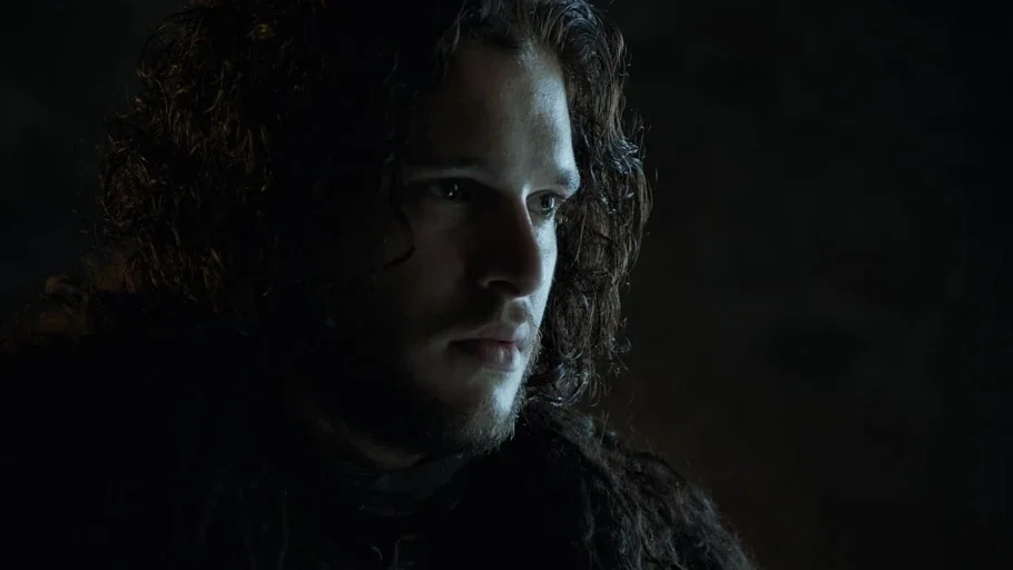 Game of Thrones (2015) movie still: closeup — A dark stone interior serves as the backdrop for a close-up portrait. A young man with long dark hair…