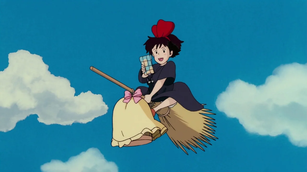 Kiki’s Delivery Service (1989) movie still: fullbody — A clear bright blue sky filled with white fluffy cumulus clouds. A young girl rides a straw…