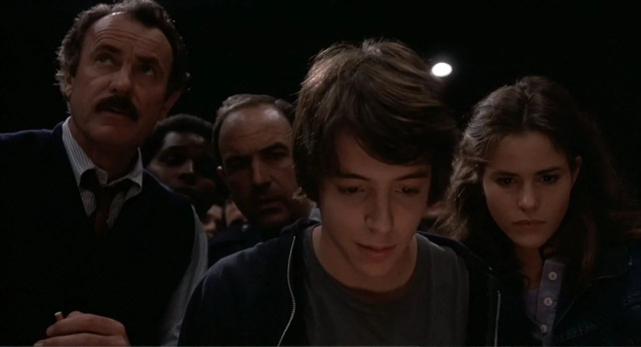 WarGames (1983) movie still: medium — A group of teenagers and men stand together in a dark nighttime setting. The subjects look forward toward an…