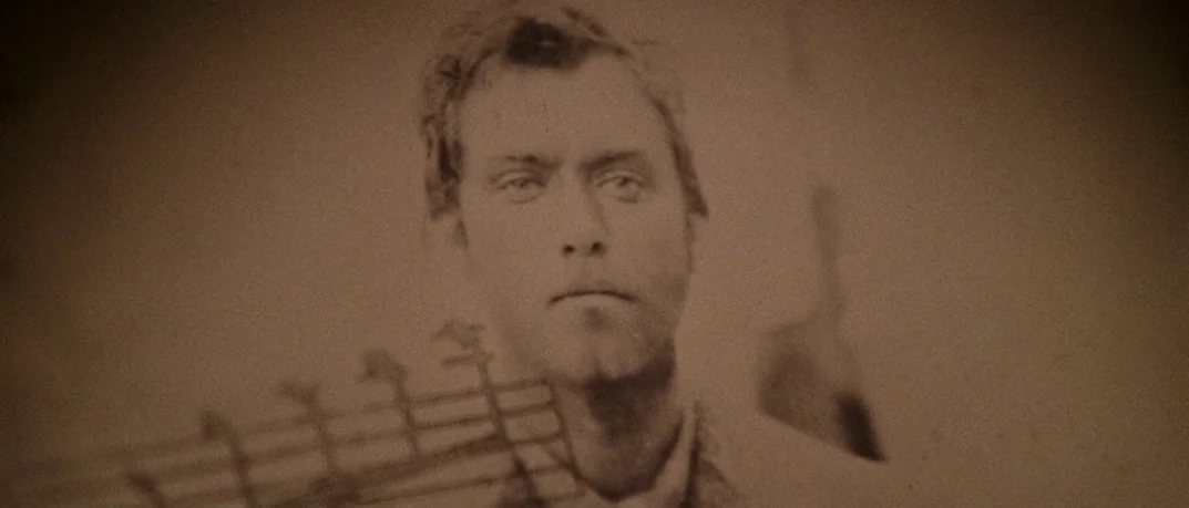 Cold Mountain (2003) movie still: closeup — An aged 19th-century sepia photograph displays a man in a textured frame. The man poses for a portrait…