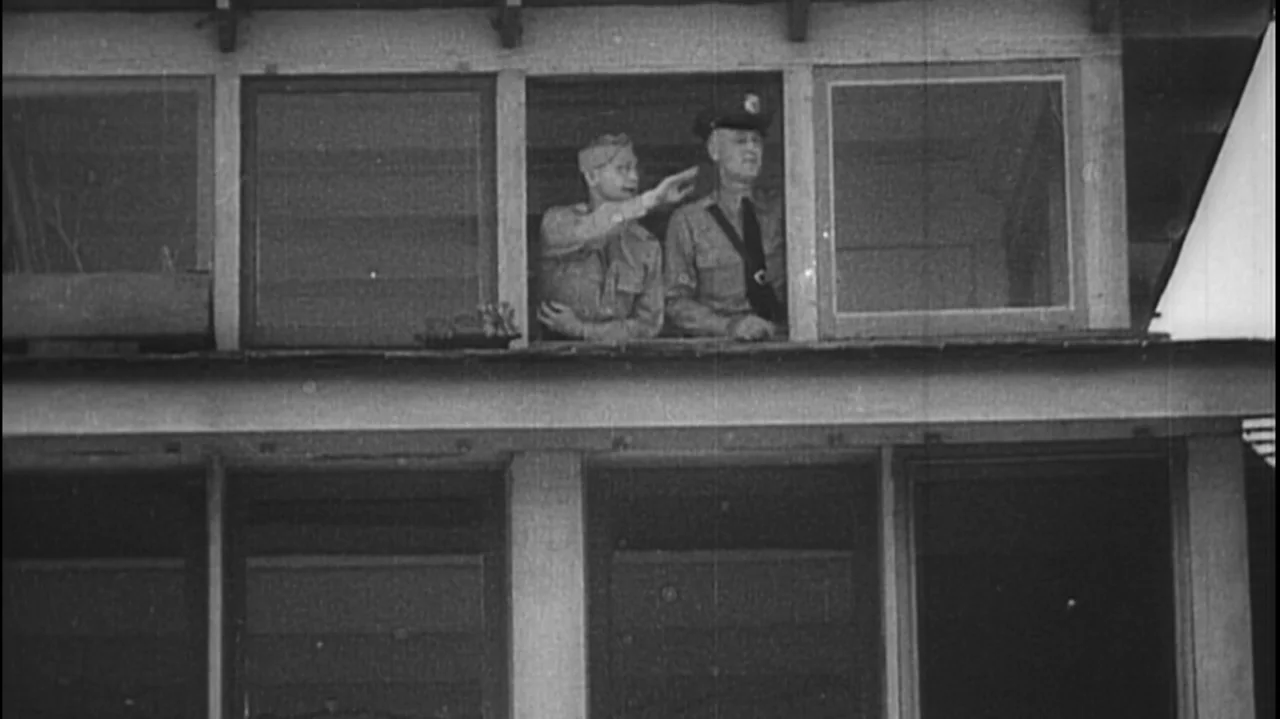 The Soul of America (2020) movie still: medium — A two-story building features a large upper-level window with framed glass panes. Two uniformed men…