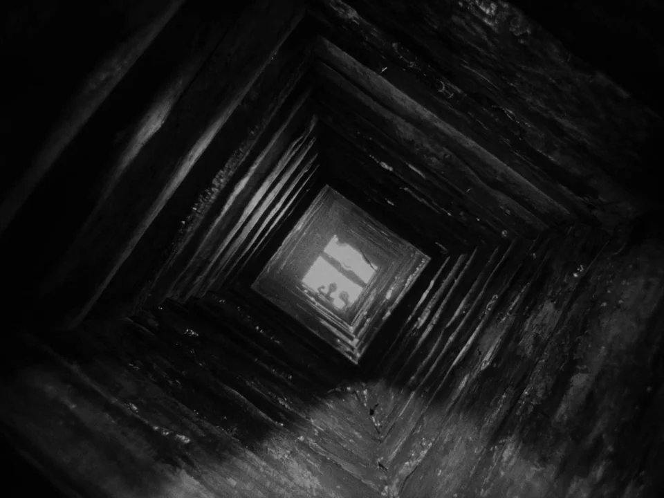 Ivan’s Childhood (1962) movie still: establishing — A vertical wooden structure tapers toward a distant, small square opening at the top. The…