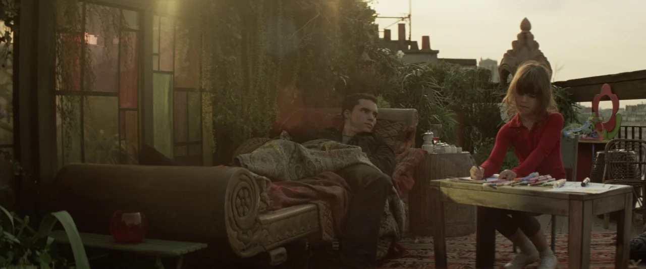 Colt 45 (2014) movie still: wide — A rooftop terrace filled with lush potted plants and a decorative stained glass partition. A man reclines on a…