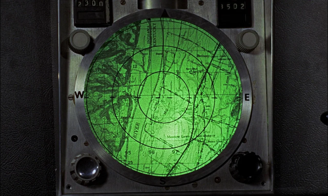 Goldfinger (1964) movie still: closeup — A close-up shot shows a circular radar display embedded within a metallic console frame. The screen glows…