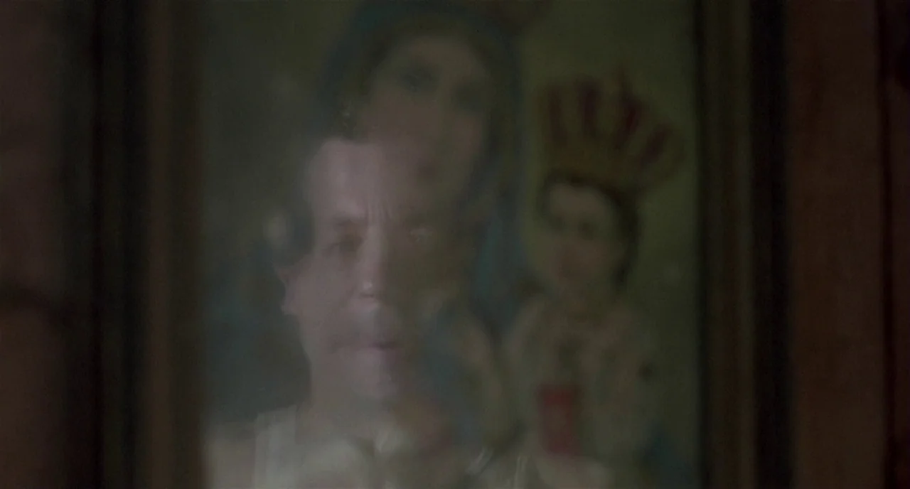Three Colours: White (1994) movie still: closeup — A dimly lit room contains a mirror reflecting a man and a religious painting. The man stares…