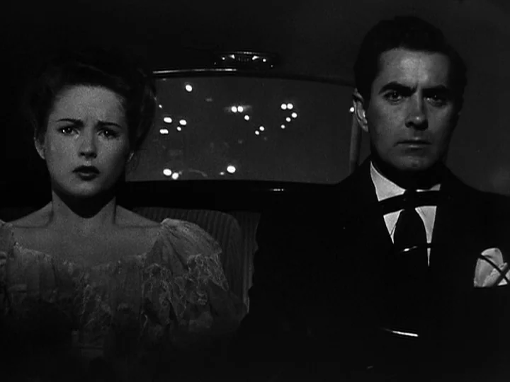 Nightmare Alley (1947) movie still: medium — A woman and a man sit inside a dark vehicle at night. The man holds the steering wheel while looking…