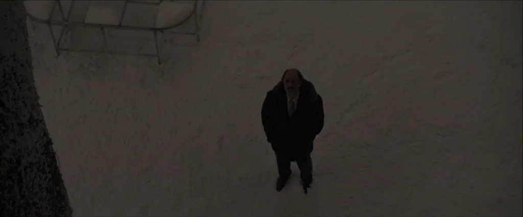 Let Me In (2010) movie still: wide — A man stands alone in a vast, dark, snow-covered area at night. He is positioned in the center of the frame…