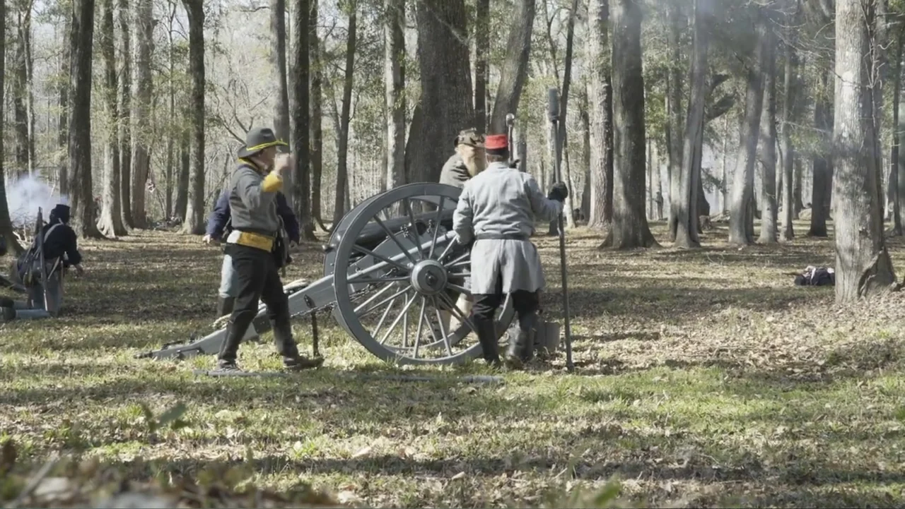 Kill Cavalry (2021) movie still: medium — A dense forest clearing filled with deciduous trees and leaf litter on the ground. Three men in mid-19th…
