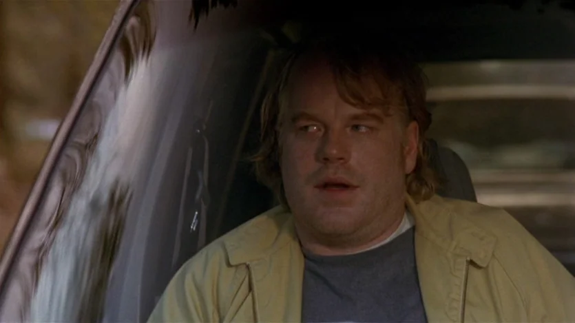 Love Liza (2002) movie still: medium — A man sits in the driver seat of a vehicle at night. The interior is dim with faint reflections visible on…