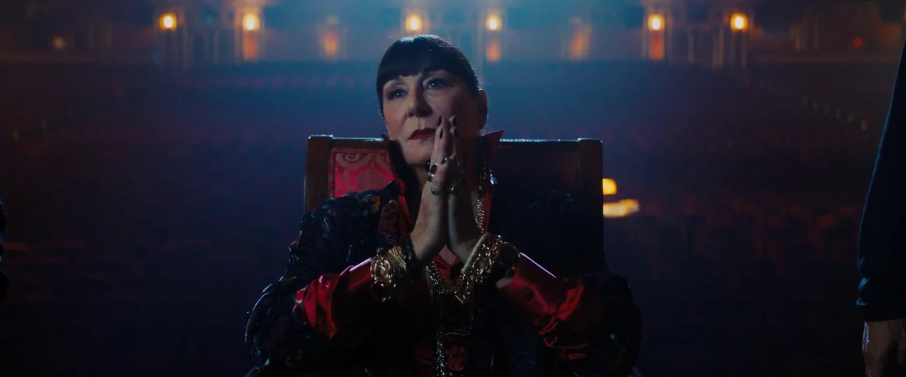 John Wick: Chapter 3 – Parabellum (2019) movie still: medium — An elderly woman sits in a plush chair within a dark, empty theater auditorium. She…