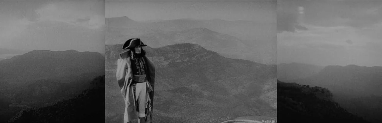 Napoleon (1927) movie still: fullbody — An expansive view of rolling mountain ranges extends into a hazy horizon. A man in 19th-century military…