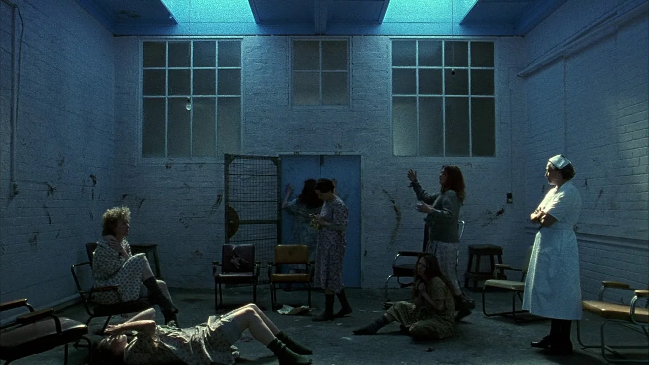 An Angel At My Table (1990) movie still: wide — A stark medical dayroom has blue-tinted light streaming down from high ceiling windows. Several…