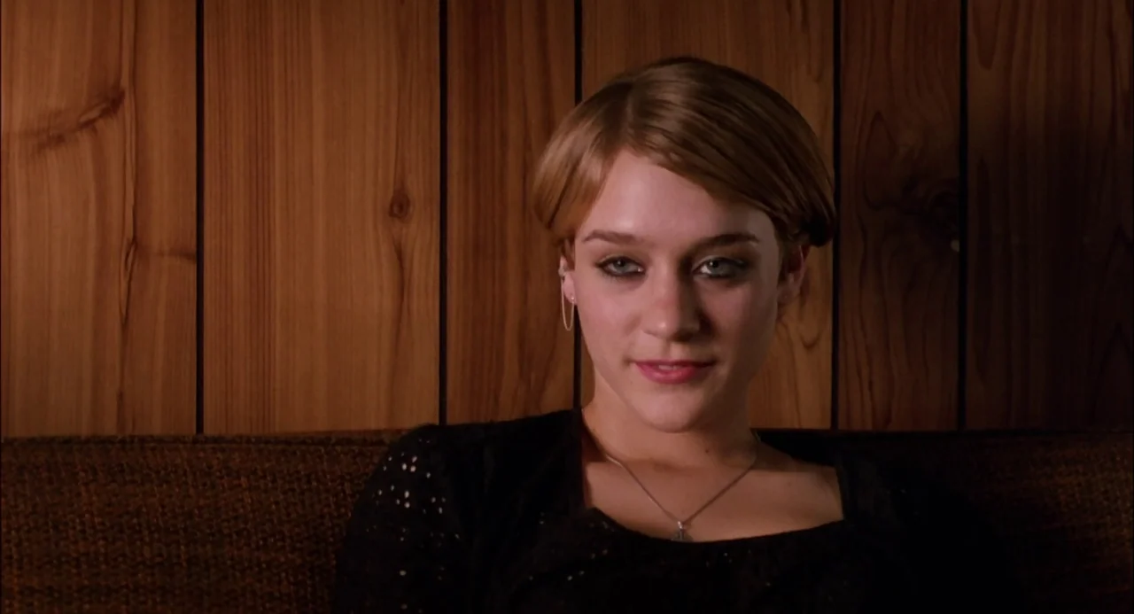 Trees Lounge (1996) movie still: medium — A woman sits before a wall of vertical light brown wood paneling. The subject remains stationary while…