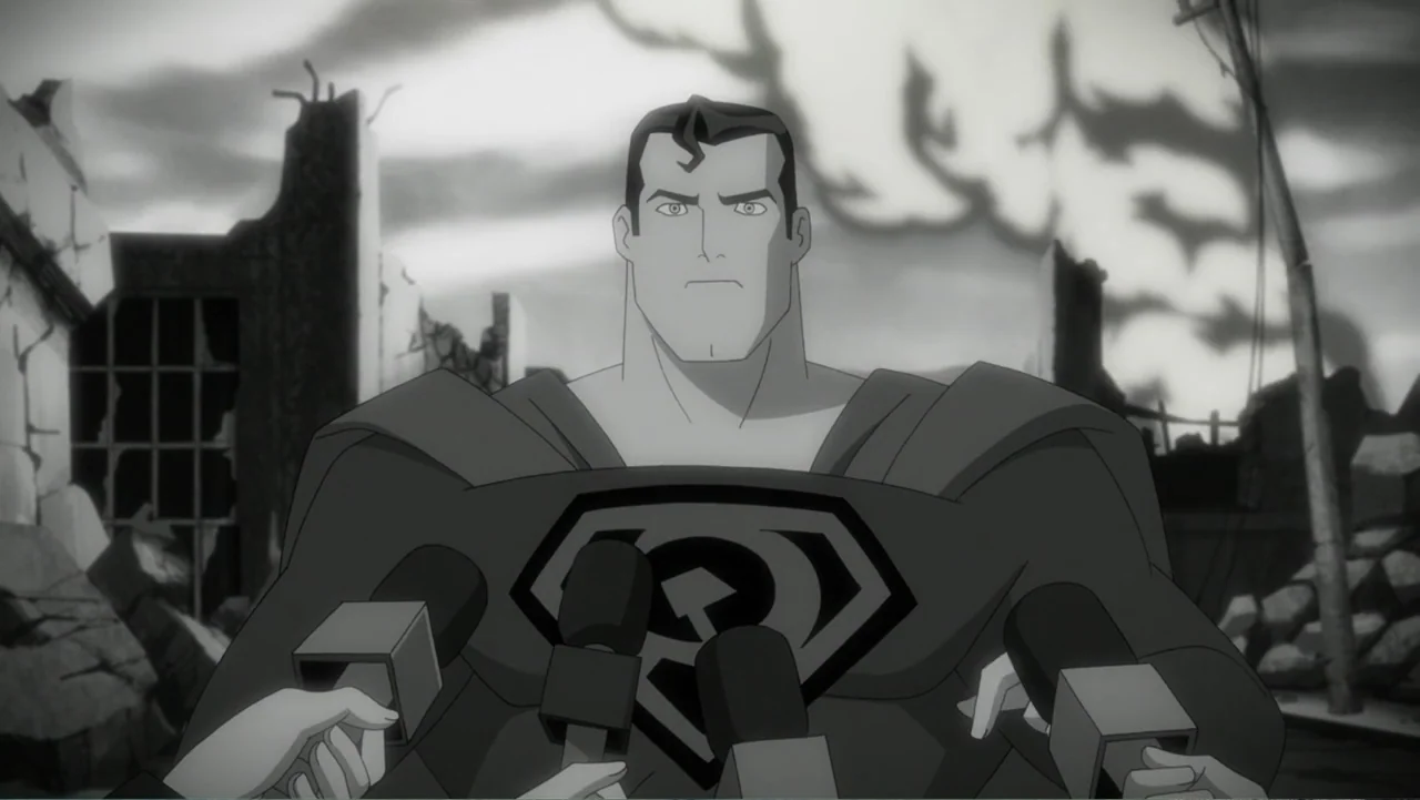 Superman: Red Son (2020) movie still: medium — A man stands in the middle of a ruined city with piles of rubble. Multiple handheld microphones are…