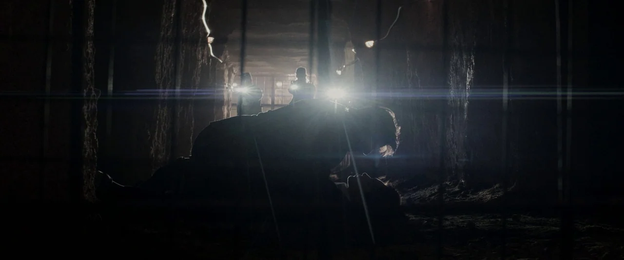 Mission: Impossible – Dead Reckoning Part One (2023) movie still: medium — A dark subterranean passage with rough earthen walls and a metal grate…