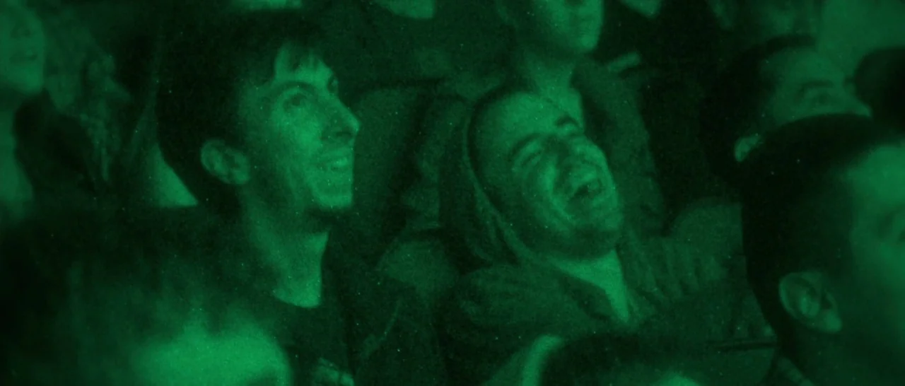 The Disaster Artist (2017) movie still: medium — A group of people sit in a dark movie theater with rows of seats. The audience is illuminated by…