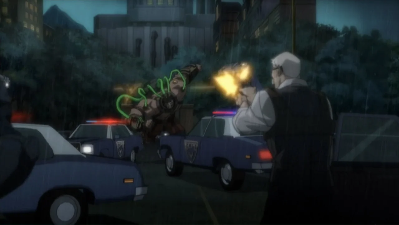 Batman: Assault on Arkham (2014) movie still: medium — A rain-slicked urban parking lot at night features police cars and concrete structures. A man…