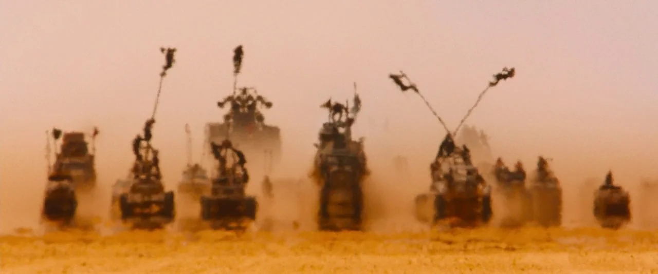 Mad Max: Fury Road (2015) movie still: wide — A vast desert landscape filled with a dense sandstorm clouding the visibility. Multiple modified…