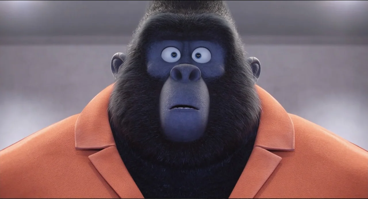 Sing (2016) movie still: closeup — A featureless indoor wall serves as a backdrop for a large anthropomorphic gorilla. The gorilla wears an orange…