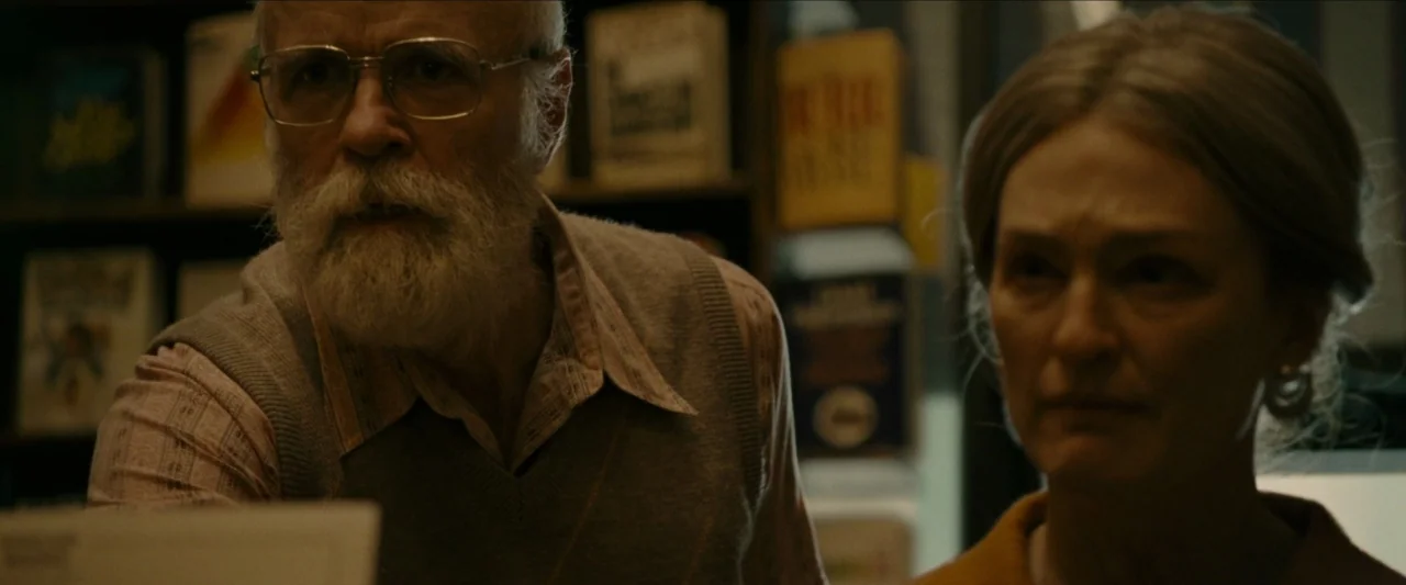 Wonderstruck (2017) movie still: medium — A dimly lit room features shelves filled with books and various printed materials. An elderly man and…