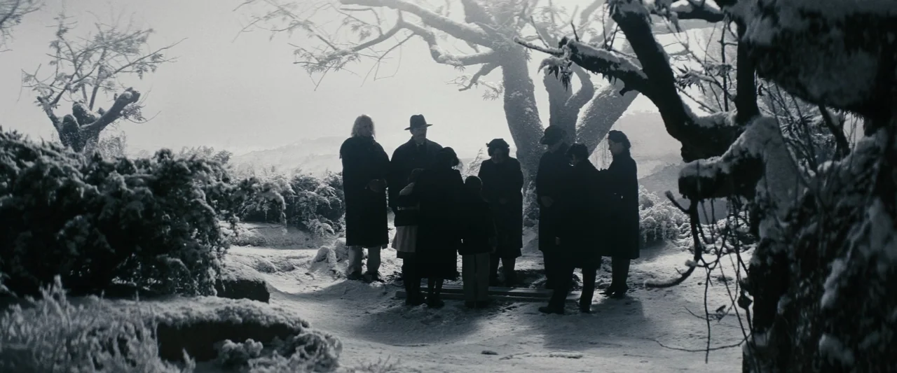 Chicken With Plums (2011) movie still: wide — A group of people stands in a circle outdoors in a snow-covered cemetery. They gather around a small…