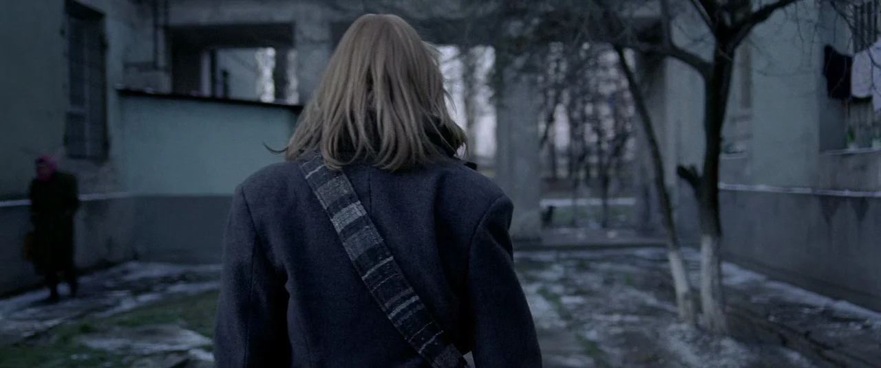 4 months, 3 Weeks and 2 Days (2007) movie still: medium — A concrete courtyard sits between weathered apartment buildings on an overcast, grey day.…