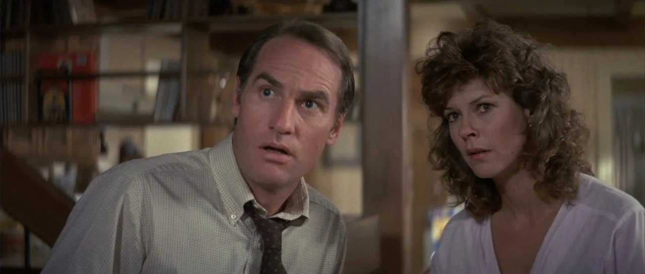 Poltergeist II: The Other Side (1986) movie still: medium — An interior residential space with blurred wooden shelves and furniture in the…