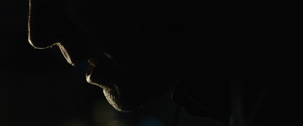 Wildling (2018) movie still: closeup — A dark environment masks the majority of the subject and setting. Only the profile of the lower face remains…