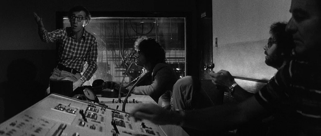 Manhattan (1979) movie still: medium — A dimly lit professional recording studio features a large central audio mixing console. Three men are…