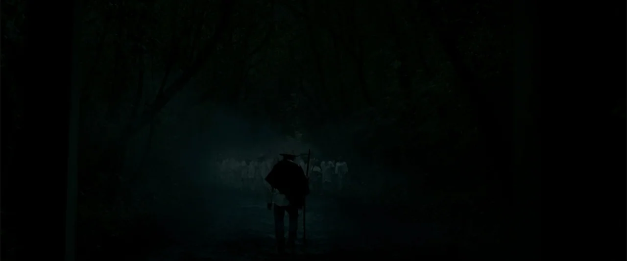 I Dream in Another Language (2017) movie still: wide — A dark, narrow dirt path winds through a dense, foggy tree-lined corridor at night. A single…
