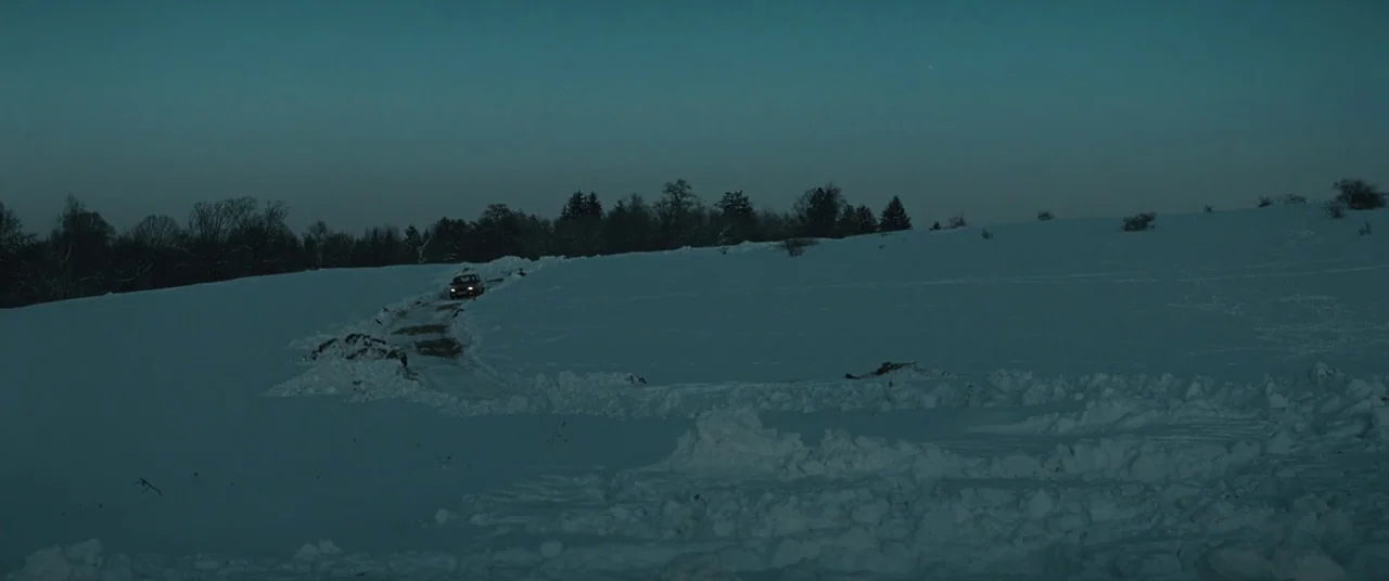 Beyond the Hills (2012) movie still: establishing — A vast, open landscape is blanketed in deep snow under a dim twilight sky. A single small…