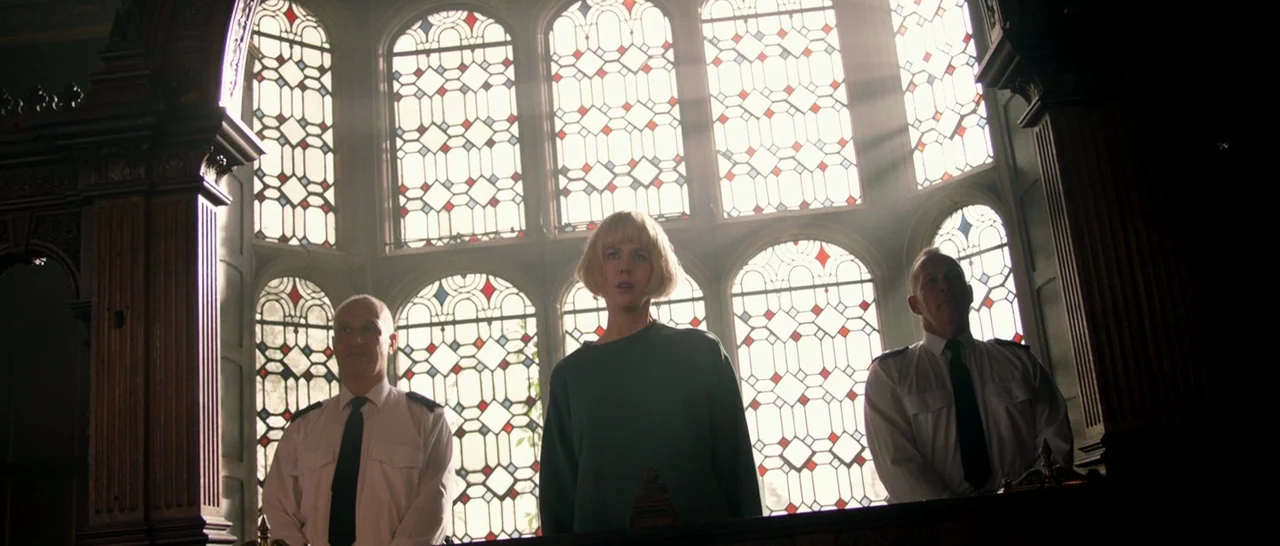 Paddington (2014) movie still: medium — A gothic-style interior with massive stained glass windows and dark wood architectural features. A woman is…