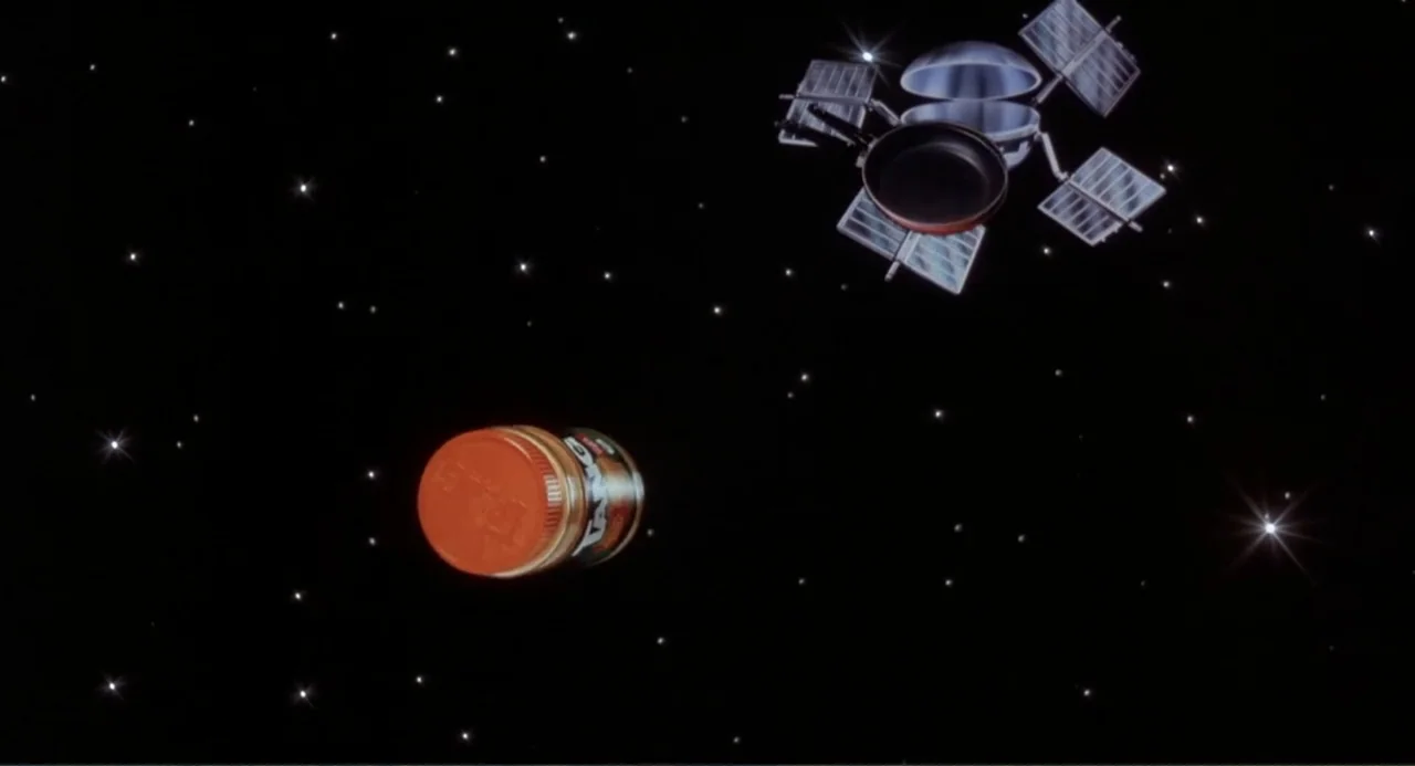 Making Mr. Right (1987) movie still: establishing — A dark, star-filled field of outer space serves as a vacuum setting. A jar of Tang and a metal…