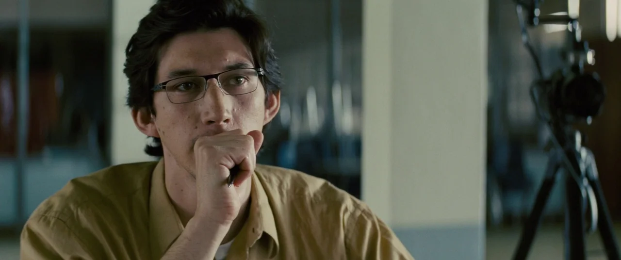 Midnight Special (2016) movie still: medium — A man sits at a desk in a modern office space with glass partitions. He rests his chin on his hand…
