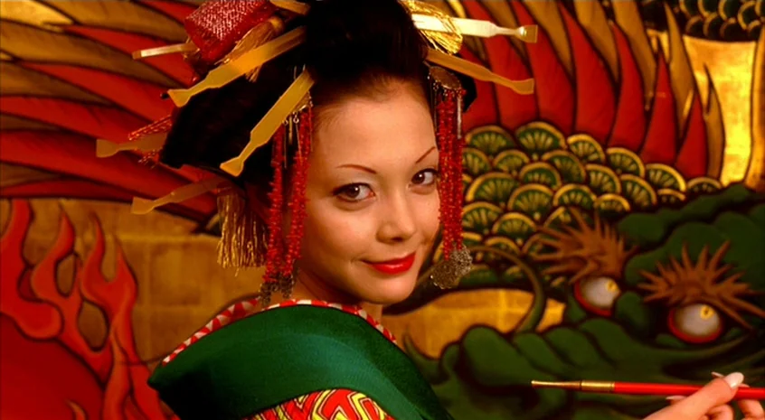 Sakuran (2006) movie still: closeup — A close-up shot of a woman in traditional Japanese formal makeup and hair accessories. She gazes directly into…