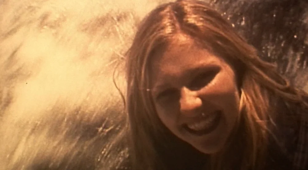 The Virgin Suicides (1999) movie still: closeup — A teenage girl appears in close proximity with water spray splashing in the background. She smiles…