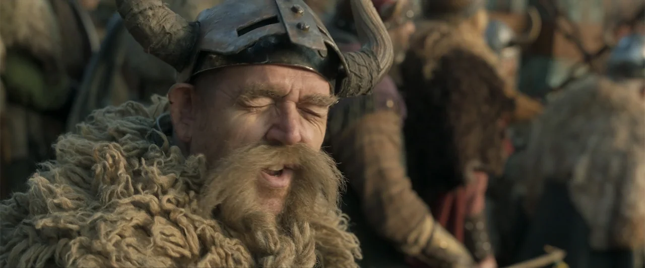 How to Train Your Dragon (2025) movie still: closeup — A crowded medieval battlefield features warriors gathered outdoors during the day. A bearded…