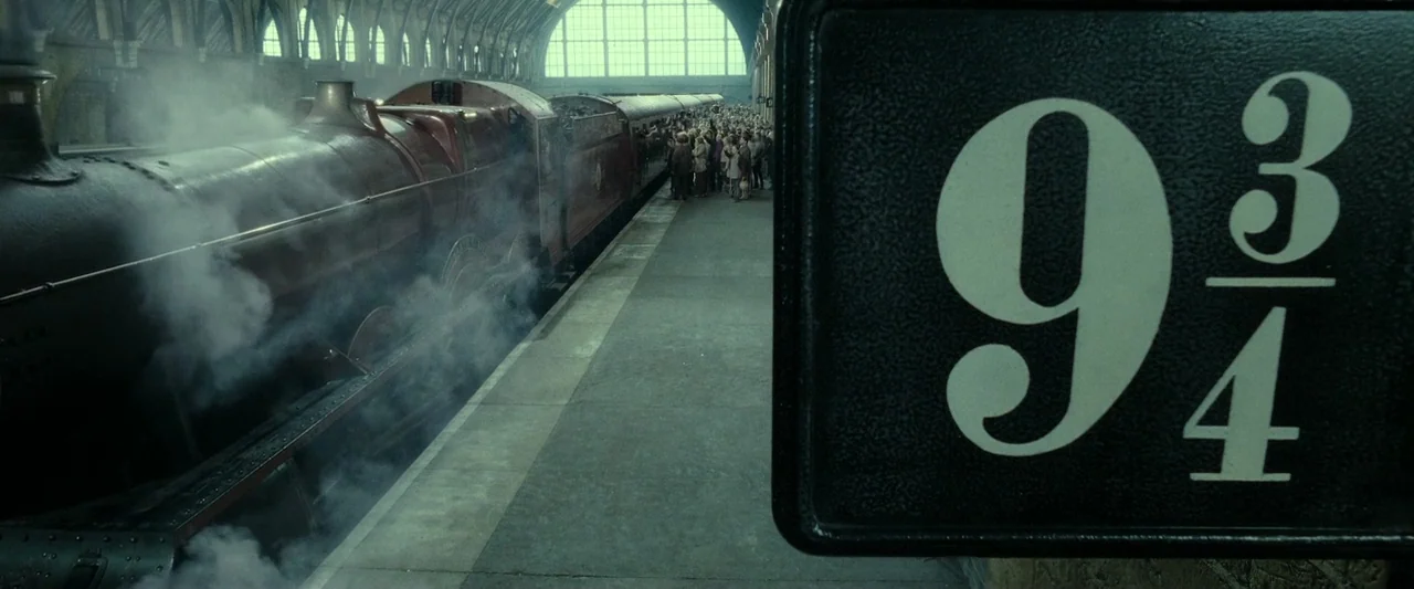 Harry Potter & The Deathly Hallows Part 2 (2011) movie still: wide — A historic brick train station features a large steam locomotive docked at a…