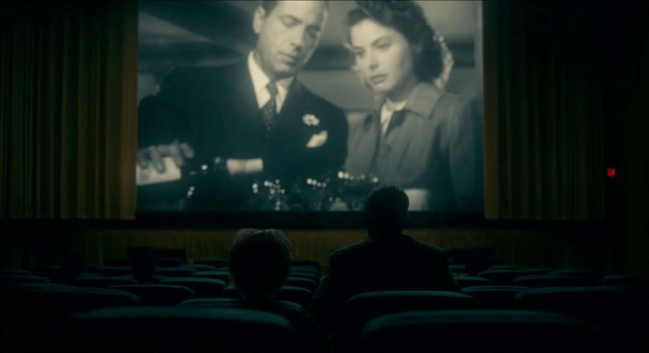 Doctor Sleep movie still: wide — A dark movie theater features rows of empty seats facing a large illuminated screen. Two people sit in the…