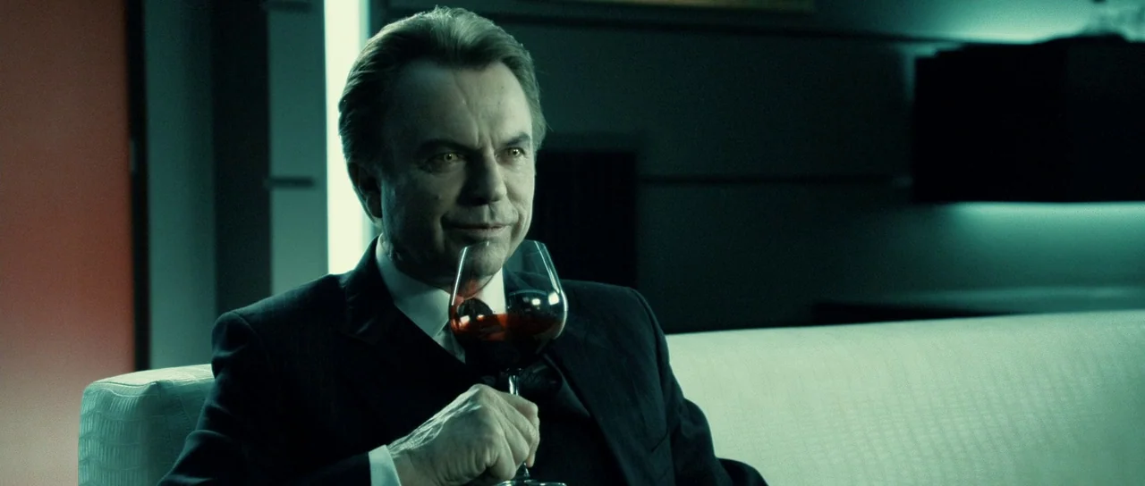 Daybreakers (2009) movie still: medium — A dark, modern lounge interior features minimalist horizontal wall panels and muted lighting. An older man…