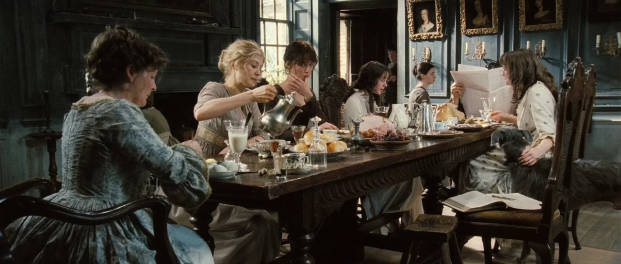 Pride & Prejudice (2005) movie still: wide — A group of women sit around a long heavy wooden table laden with food. They dine in a formal room with…
