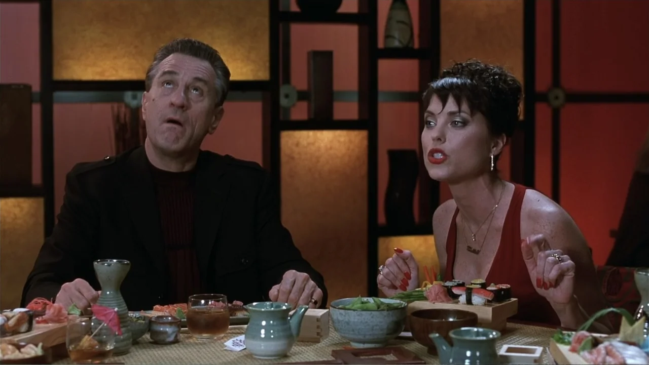 Analyze That (2002) movie still: medium — A dimly lit sushi restaurant features dark wooden lattice partitions with warm backlit panels. A man and a…