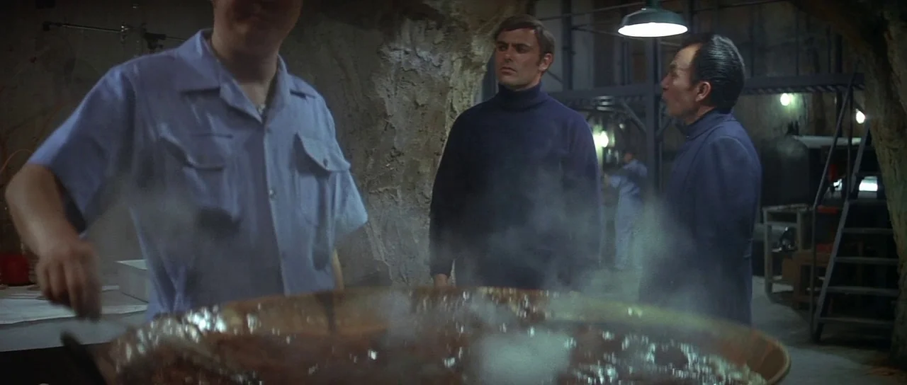 Enter The Dragon (1973) movie still: medium — A subterranean room with raw concrete walls and industrial metal equipment setup. A large metal pot…