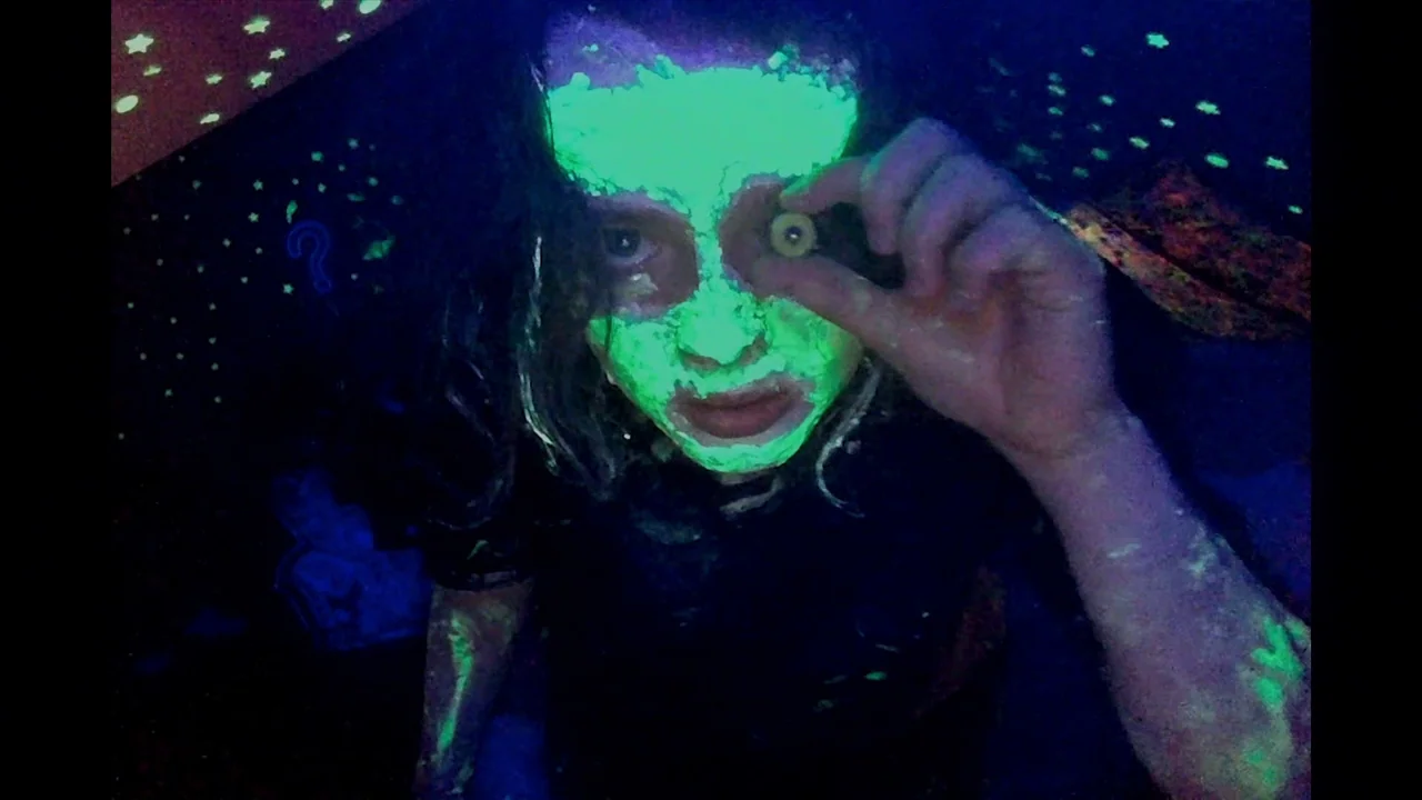 We’re All Going to the World’s Fair (2021) movie still: closeup — A dark bedroom with glow-in-the-dark stars stuck to the ceiling. A girl with face…