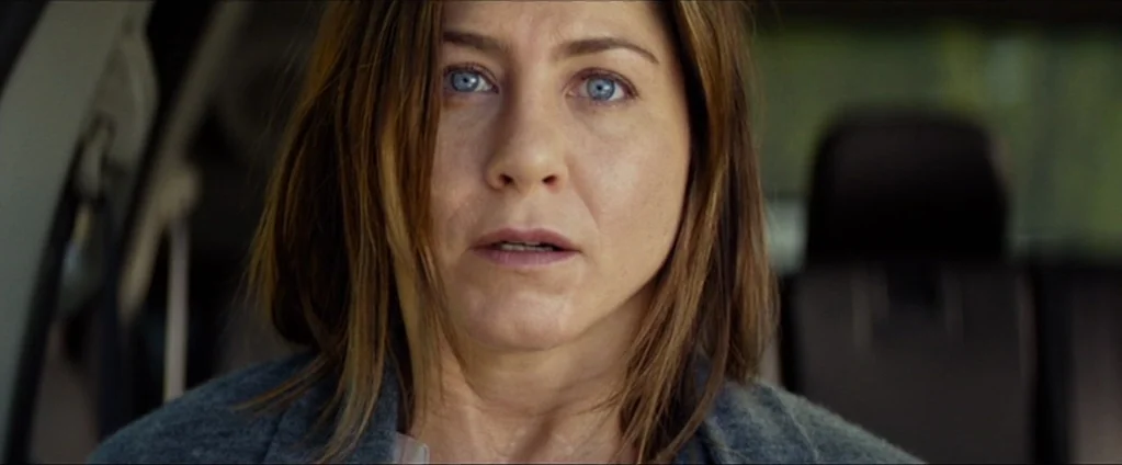Cake (2014) movie still: closeup — The interior of a car with a grey seat and dark headrest visible. A middle-aged woman with blue eyes looks forward.