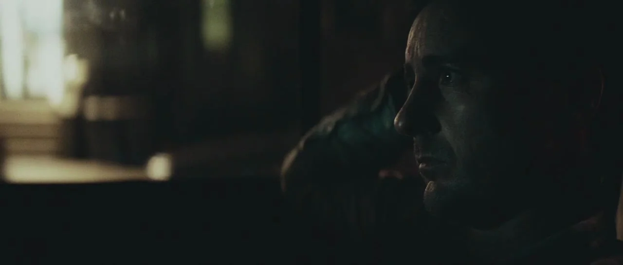 Meadowland (2015) movie still: closeup — A dimly lit cabin of a vehicle is dark with minimal ambient light. A man sits in the passenger seat with…