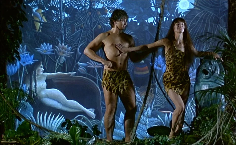 Jane B. par Agnès V. (1988) movie still: fullbody — A theatrical stage displays a large backdrop of a jungle with painted exotic flora. A man and…