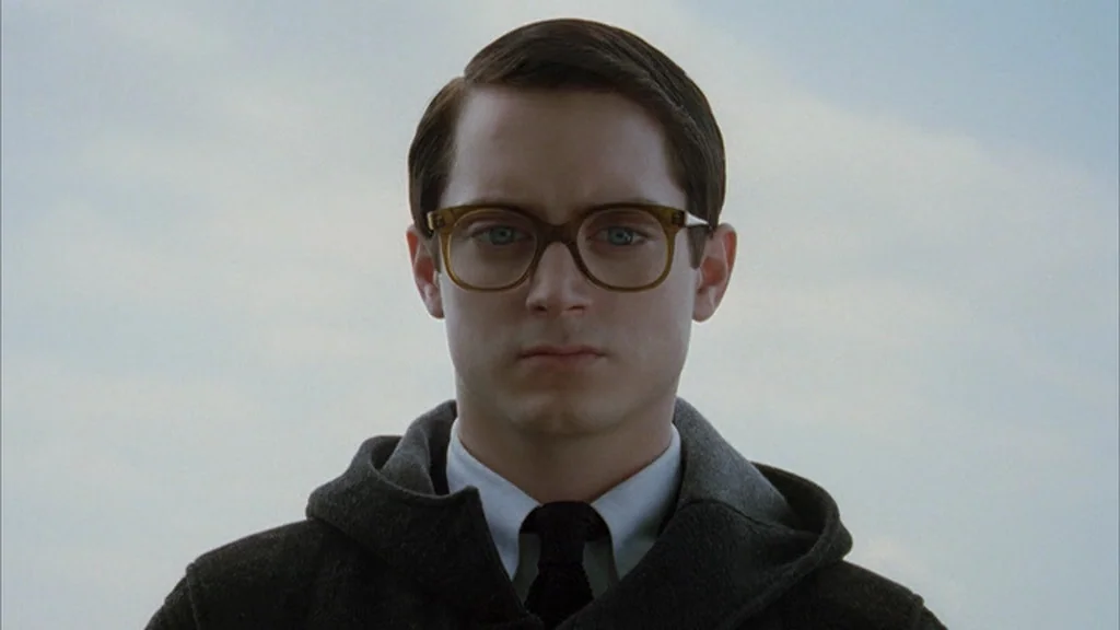 Everything Is Illuminated (2005) movie still: closeup — An overcast, featureless sky forms the backdrop for a portrait of a young man. The man gazes…