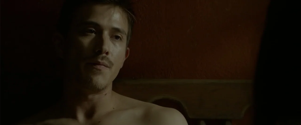 I Dream in Another Language (2017) movie still: closeup — A dimly lit room features a man resting against a plain wall. The man sits shirtless, his…