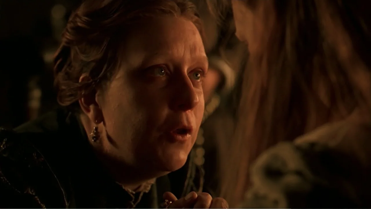Elizabeth (1998) movie still: closeup — A dimly lit indoor space with shadows obscuring the background. A woman leans toward another person while…
